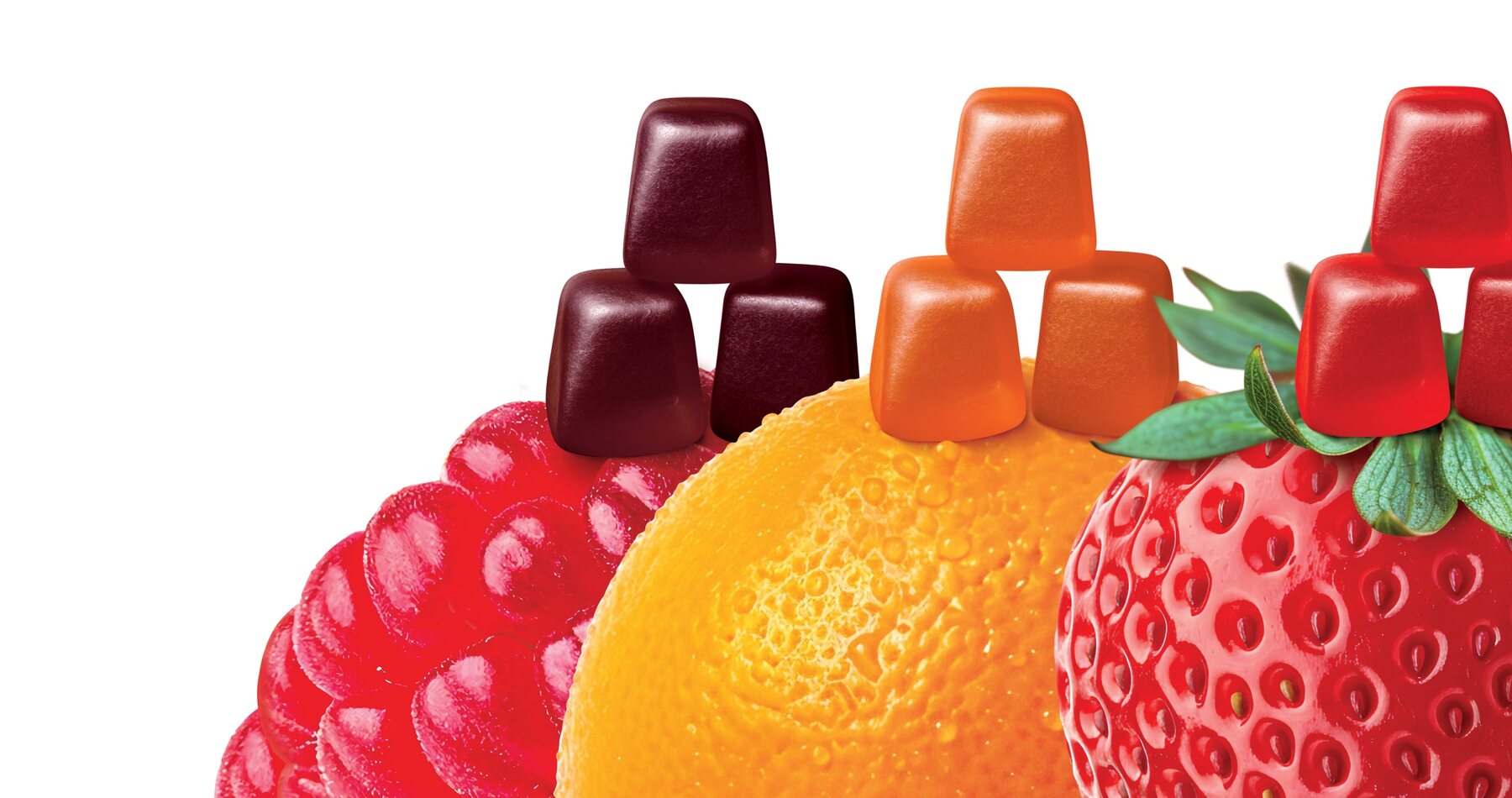 Lioness gummies resting on oversized raspberry, orange and strawberry